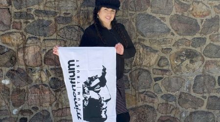 Woman wearing all black and holding a white tea towel with the Trimontium logo on.