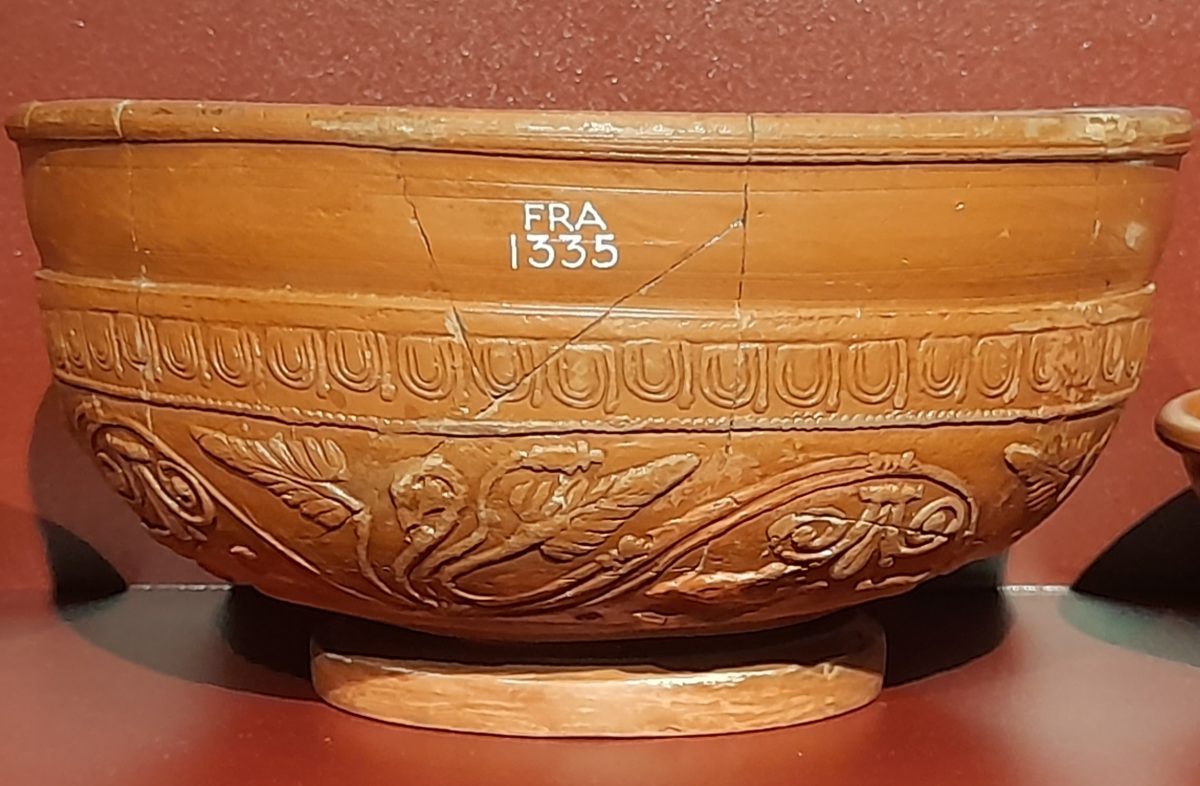A terracotta coloured Samian ware bowl with decoration.