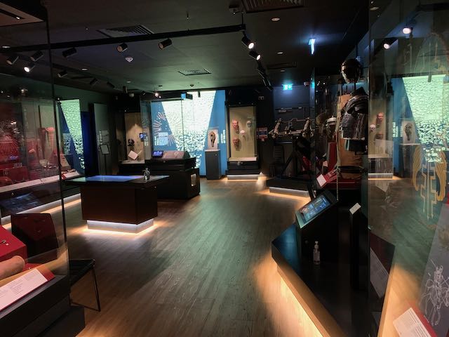 Inside the museum gallery, with displays of Roman coins and military equipment.