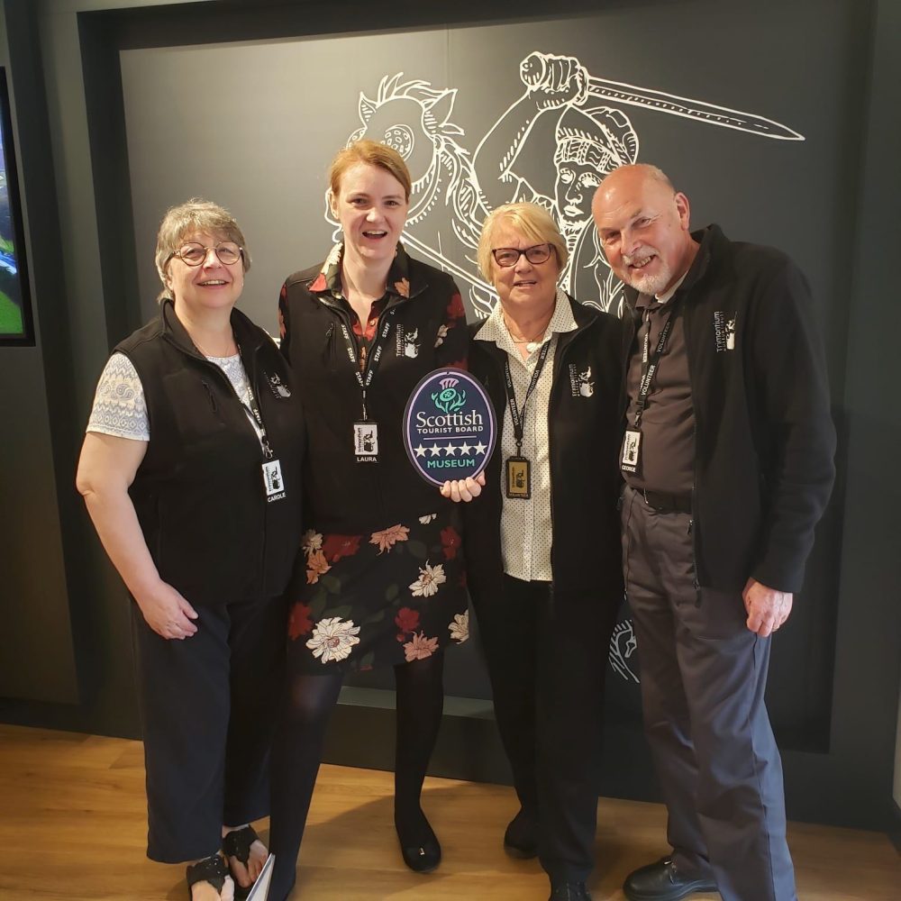 4 people holding a 5 star VisitScotland plaque.
